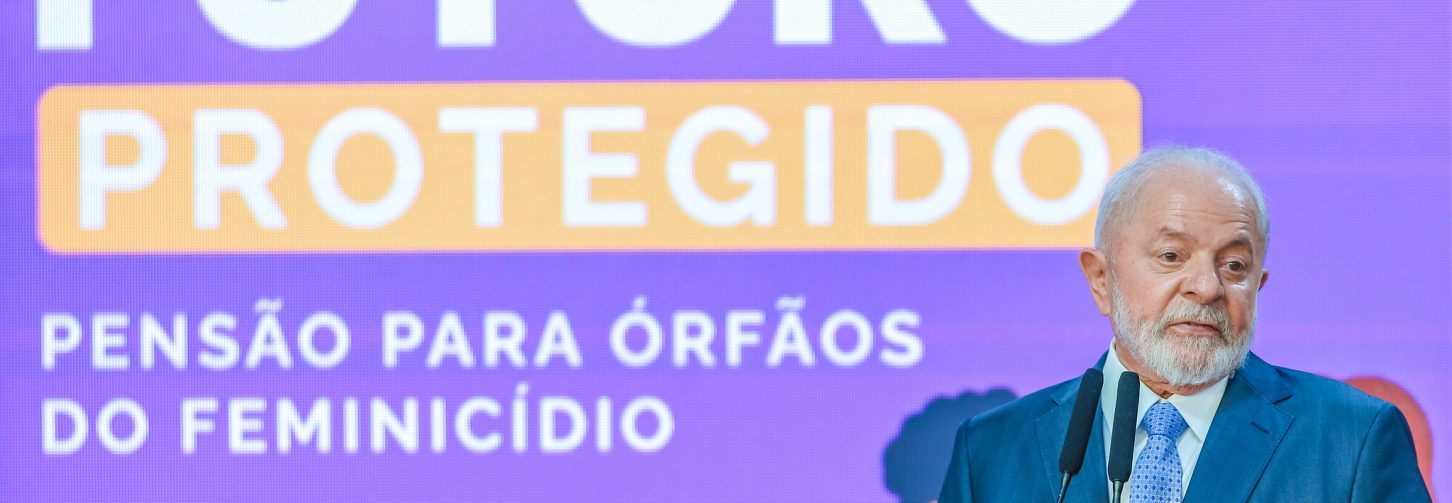 O presidente Lula fala num púlpito durante evento no Palácio do Planalto. Ao fundo, um painel com o título Futuro Protegido, relativo ao evento para sancionar lei sobre pensão para órfãos de feminicídio