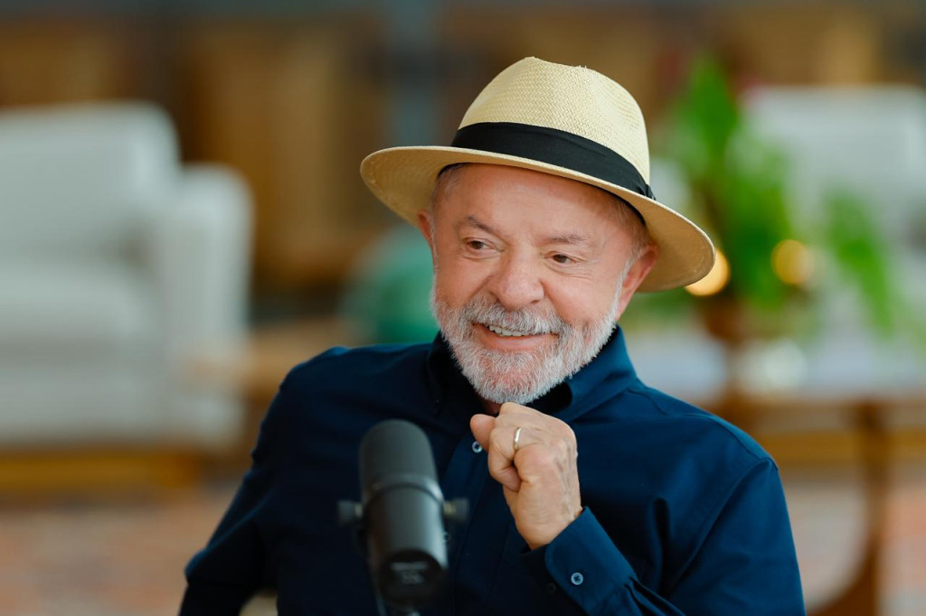 Presidente Lula de chapéu e camisa azul escura falando no microfone durante entrevista concedida ao Podcast Não Inviabilize em Brasília.
