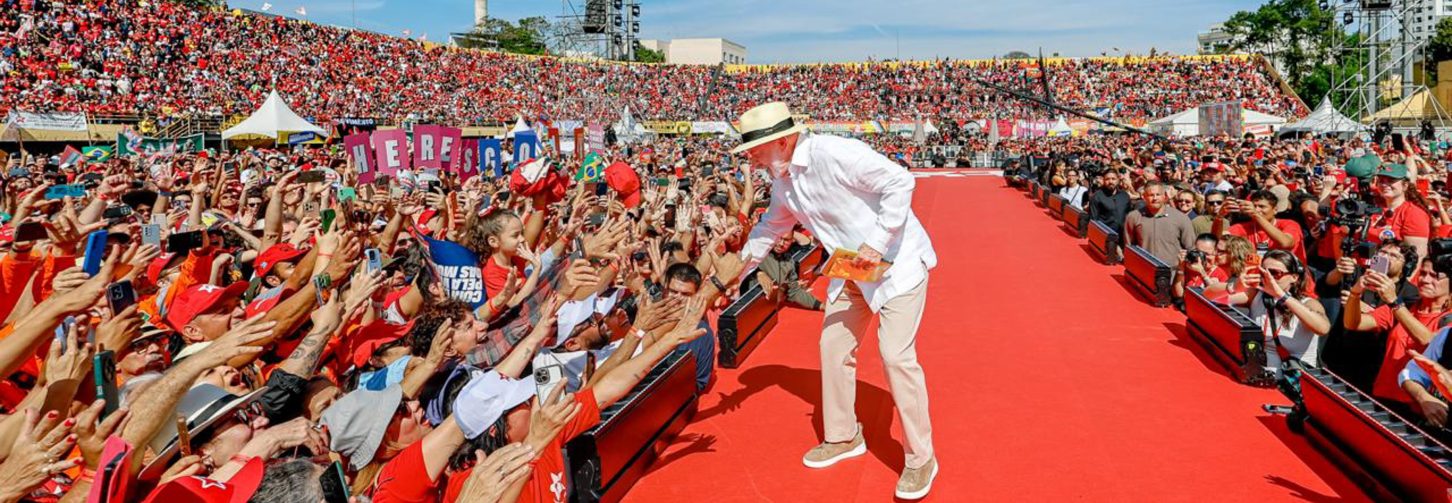 Lula em palanque cumprimentando o público no gramado do estádio Primeiro de Maio.