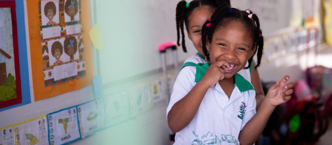 Duas crianças negras e sorrindo se abraçando na escola e de uniforme